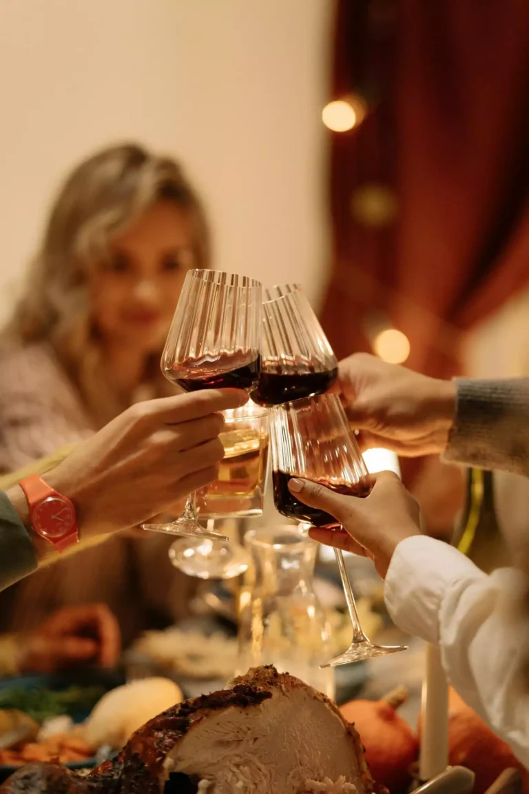 des convives à tables qui trinquent avec leur verre de vin rouge lors d'un repas festif