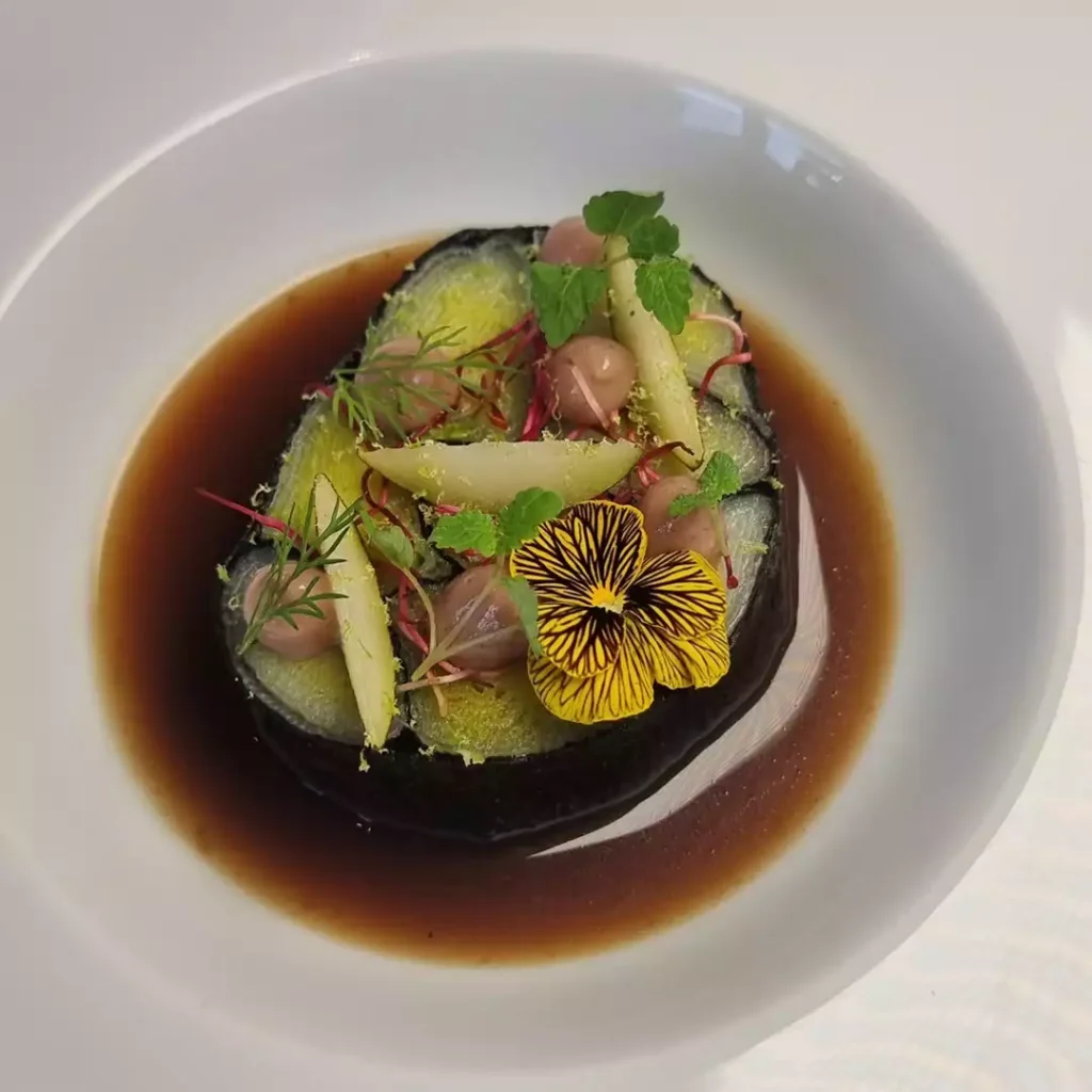 mosaique de poireau avec de l'algue nori et un bouillon confectionné par le chef johann schopff