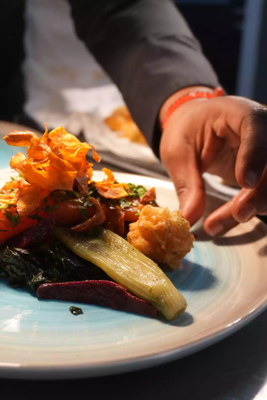 Chef privé dressant une assiette de légumes rôtis au moment du service
