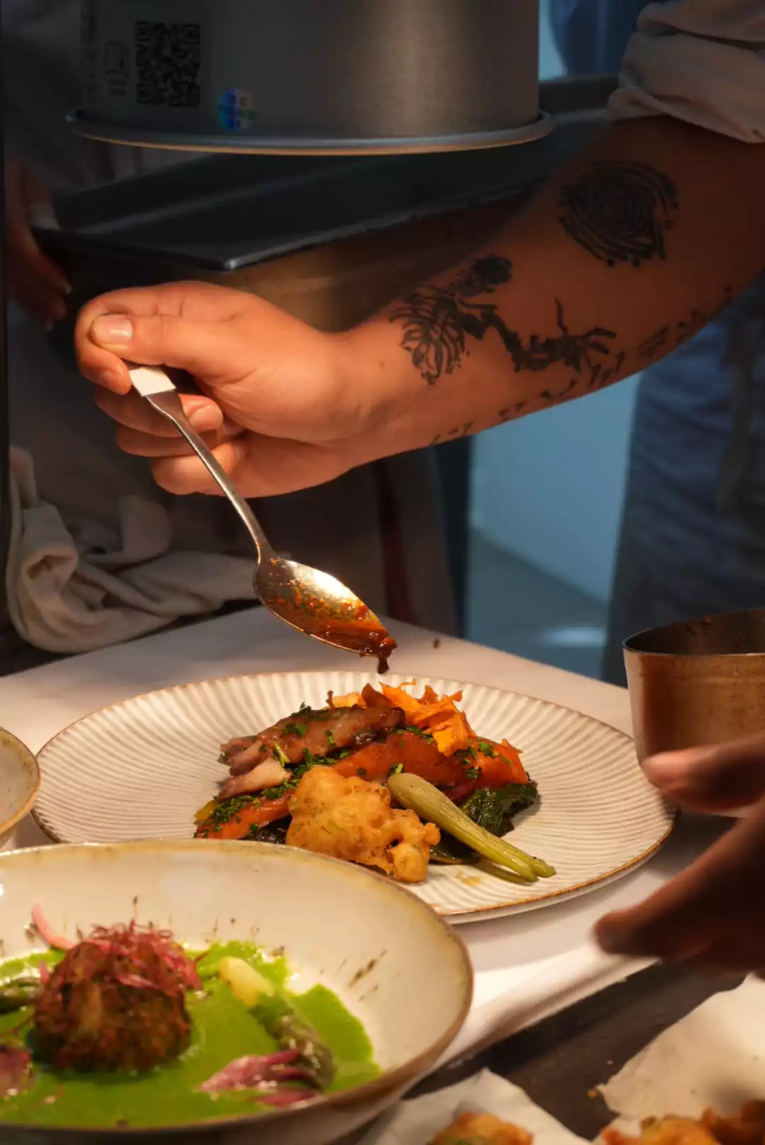 Chef privé nappant de sauce une assiette de légumes au moment du service