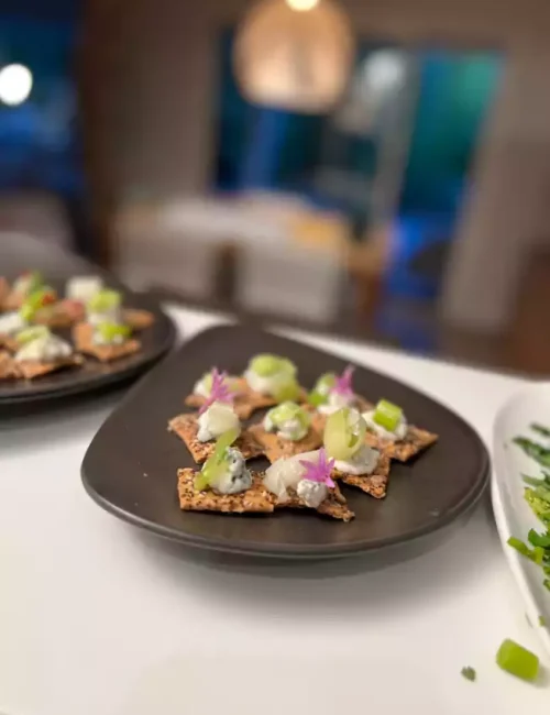 pièce cocktail avec des crackers, du fromage frais et des concombres