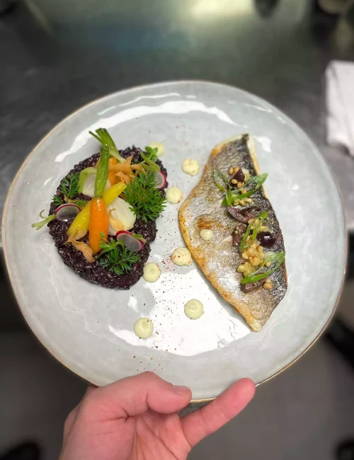 création composée d'un filet de daurade et de riz noir présenté par e chef à domicile ryad ben el haadj