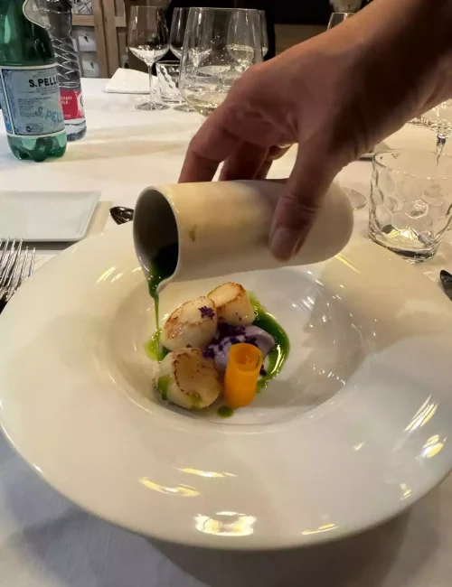les saint jacques sont présentés dans une entrée avec le service à table d'une sauce au cresson