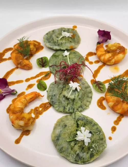 un plat représentant des ravioles et des crevettes avec un jus de crustacé par le chef à domicile thomas lecouturier